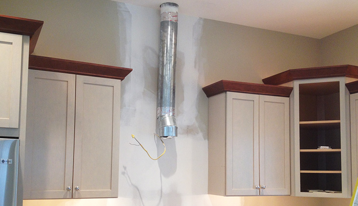 Drywall repair behind a range hood in the kitchen.